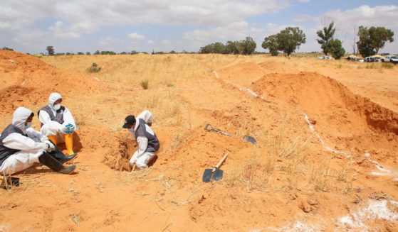 Libyan Ministry of justice employees dig out at a siyte of a suspected mass grave in the town of Tarhouna, Libya, on June 23, 2020.