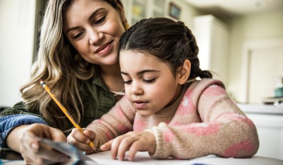 A mother helps her daughter with homework in this stock image.