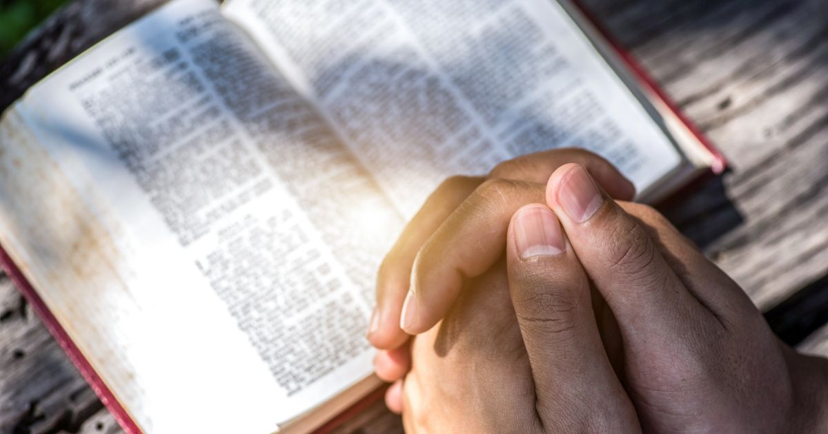 This stock image depicts someone praying with the Bible open.
