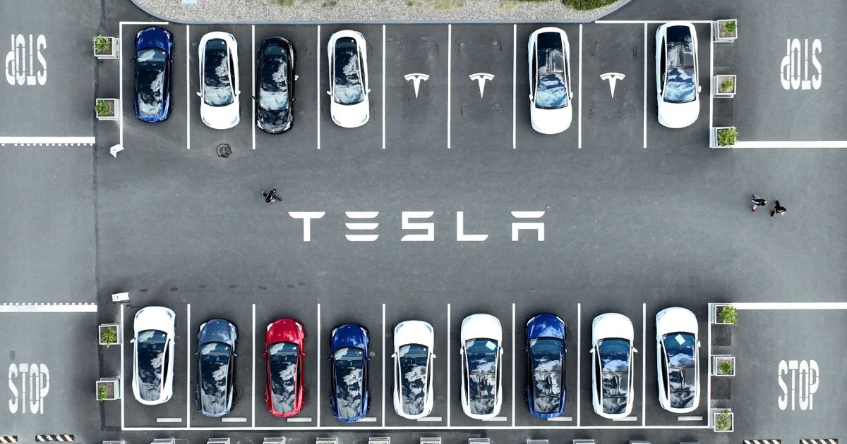 In an aerial view, Tesla cars sit parked in a lot at the Tesla factory on April 20, 2022, in Fremont, California.