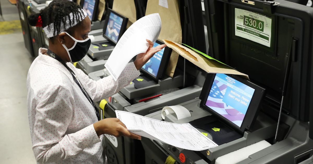 A Miami-Dade election worker feeds ballots into a voting machine during an accuracy test at the Miami-Dade Election Department headquarters on Oct. 14, 2020, in Doral, Florida.