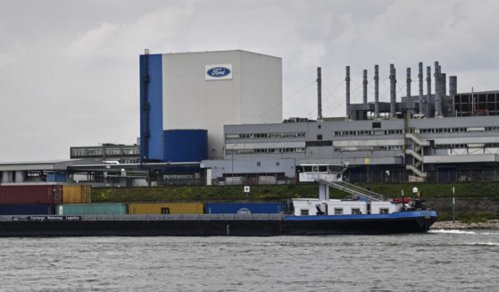 a container ship passing the Ford car plant in Cologne, Germany