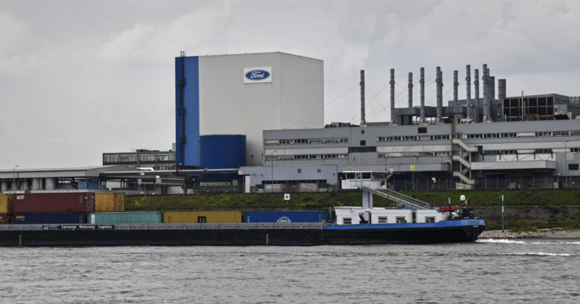 a container ship passing the Ford car plant in Cologne, Germany