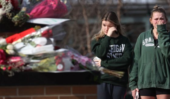 People leave flowers, mourn and pray at a makeshift memorial at the Spartan statue on the campus Michigan State University Tuesday in East Lansing, Michigan. A gunman opened fire at two locations on the campus Monday night, killing three students and injuring several others.