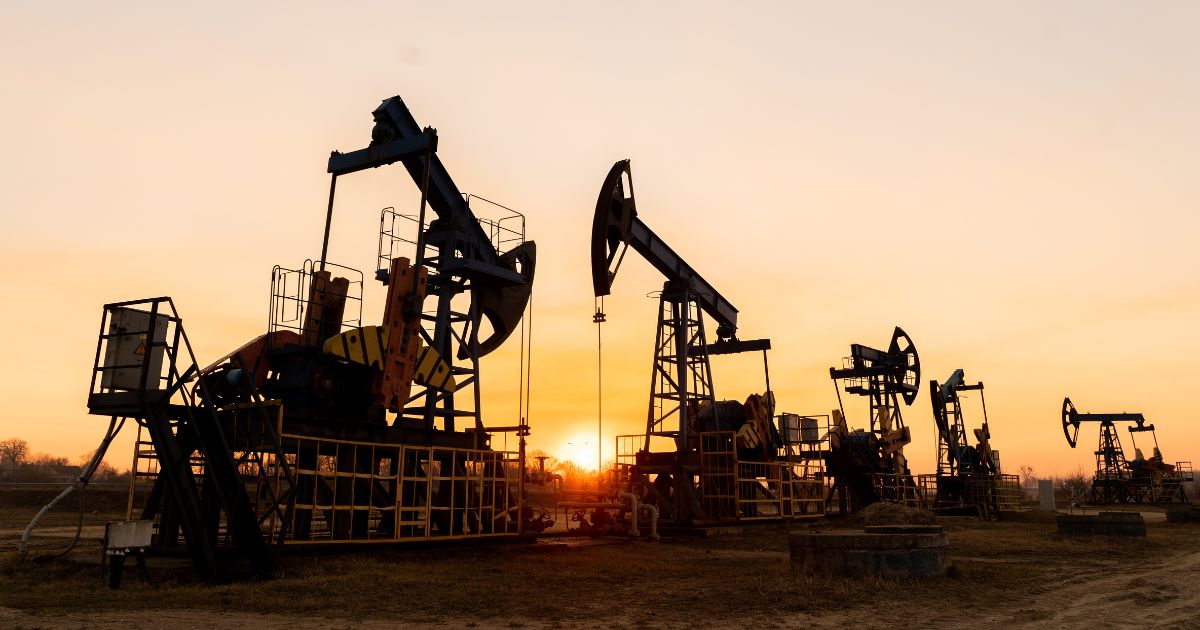 This stock photo shows oil pumps against the background of a sunset.