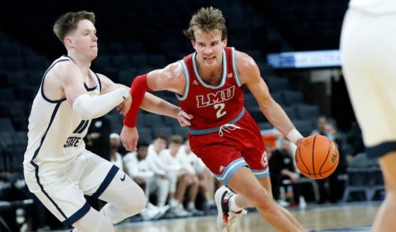 Justin Ahrens #2 of the Loyola Marymount Lions drives past Max Shulga #11 of the Utah State Aggies during the second half of a game at Michelob ULTRA Arena on Dec. 10, 2022, in Las Vegas.