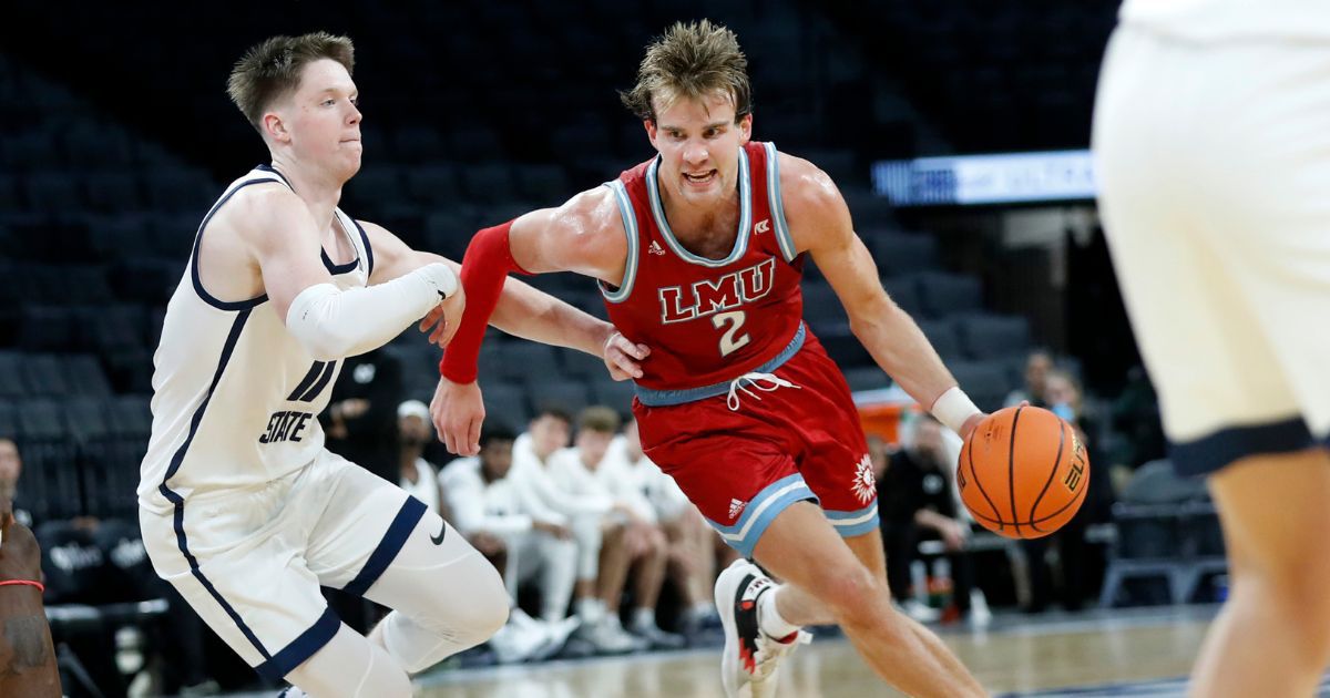 Justin Ahrens #2 of the Loyola Marymount Lions drives past Max Shulga #11 of the Utah State Aggies during the second half of a game at Michelob ULTRA Arena on Dec. 10, 2022, in Las Vegas.