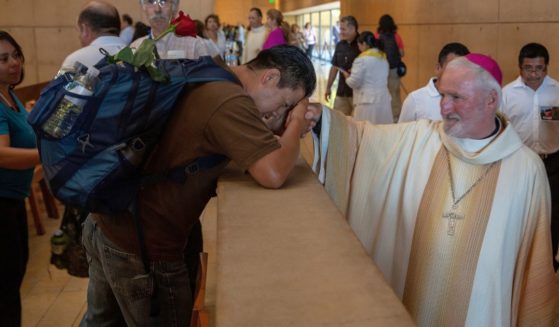 Auxiliary Bishop David O'Connell, right, from the San Gabriel Pastoral Region, is revered by an unidentified pilgrim, left, after a special "Mass in Recognition of All Immigrants'' at the Los Angeles Cathedral of Our Lady of Angels in Los Angeles on June 24, 2018.