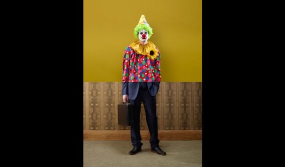 This stock image depicts a man dressed as a clown in his upper half, and a businessman in his lower half.