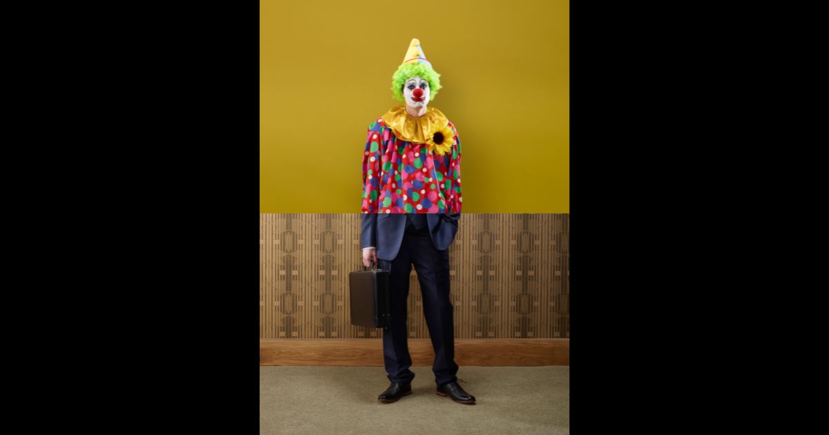 This stock image depicts a man dressed as a clown in his upper half, and a businessman in his lower half.