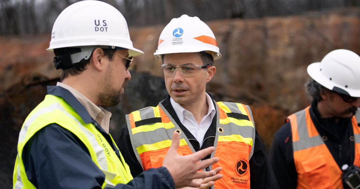 Secretary of Transportation Pete Buttigieg, center, visits with Department of Transportation Investigators at the site of the derailment on Thursday in East Palestine, Ohio.