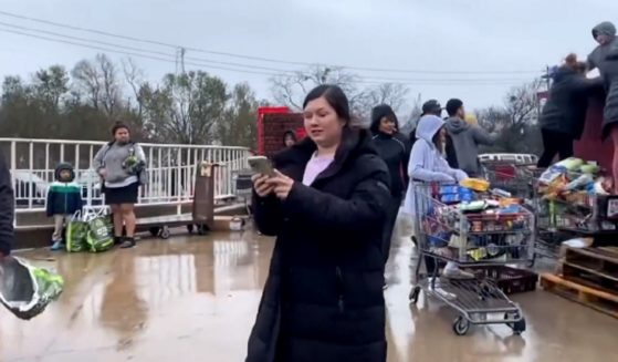 A woman uses her cell phone to record a mob of scavengers that descended on a dumpster outside a supermarket in Austin, Texas, on Thursday after the store discarded food potentially spoiled by a power outage.