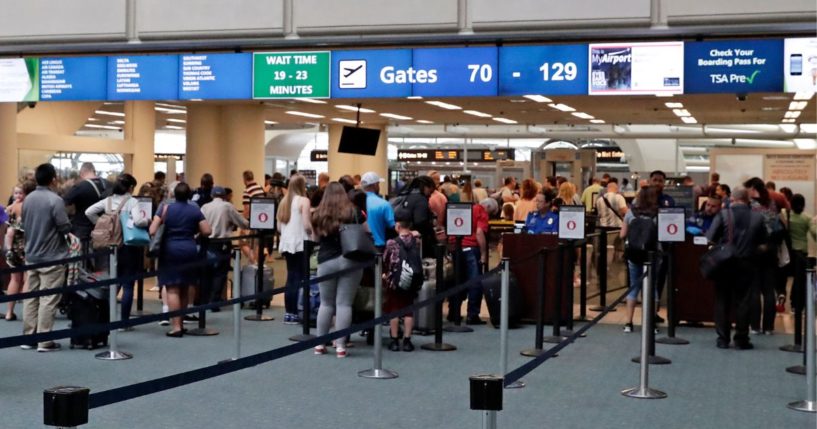 Passengers heading to their departure gates line up to go through security screening at Orlando International Airport in Orlando, Florida, on June 21, 2018.