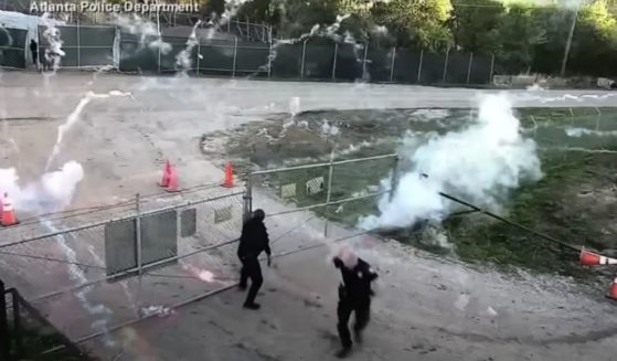 Police officers struggle to secure a gate as they are bombarded with fireworks.