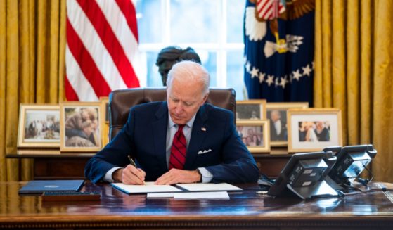 President Joe Biden signs executive actions in the Oval Office on Jan. 28, 2021.