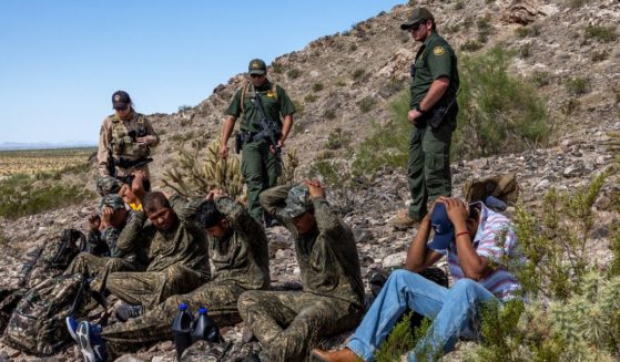 Three U.S. Customs and Border Protection agents detain a group of illegal immigrants at the Organ Pipe National Monument in Arizona on Sept. 28, 2022.