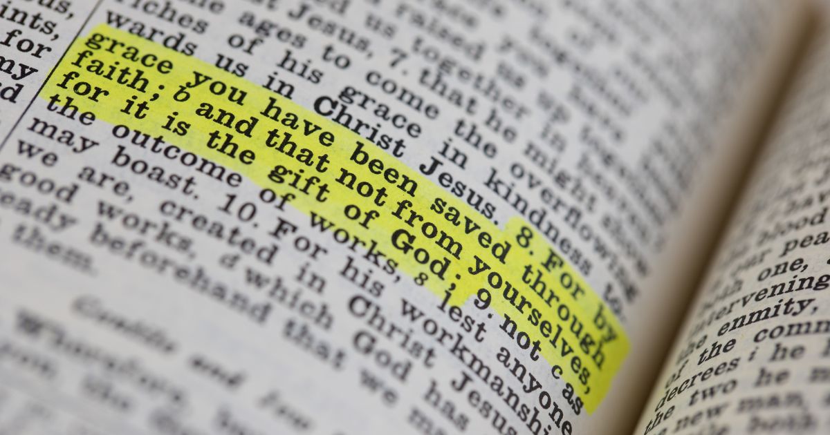 Ephesians 2:8 is highlighted in a Bible in the above stock image.