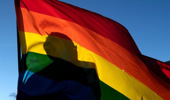 A person's silhouette is seen through an LGBT flag in Colorado Springs, Colorado, on Nov. 20, 2022.