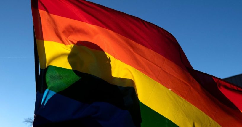 A person's silhouette is seen through an LGBT flag in Colorado Springs, Colorado, on Nov. 20, 2022.