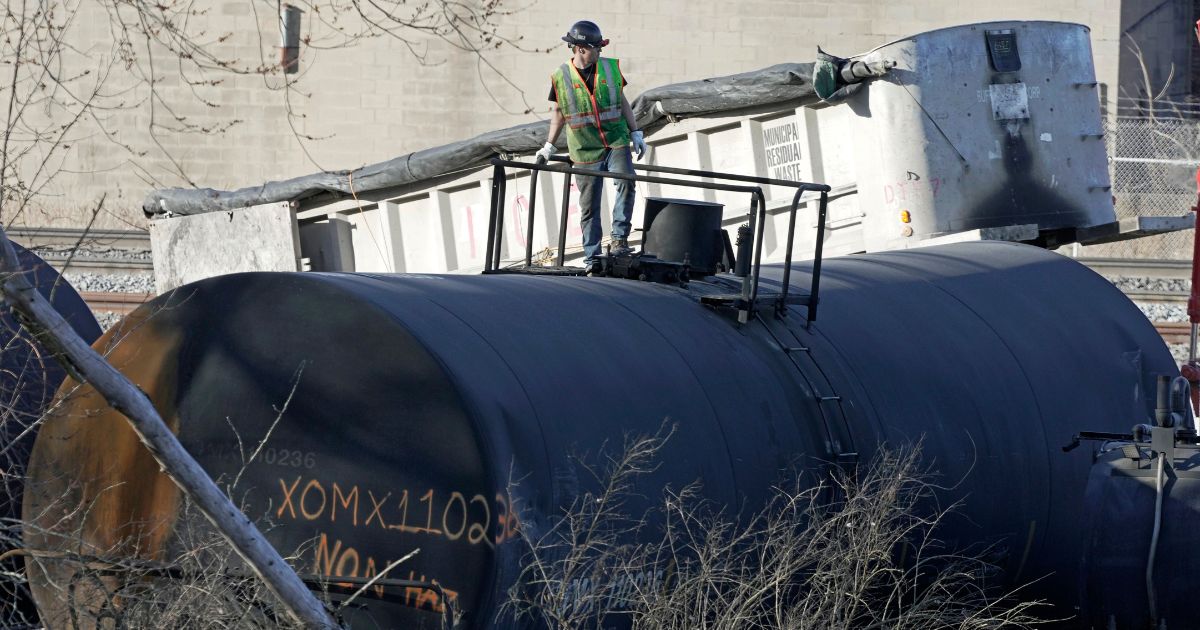 A cleanup worker stands on a derailed tank car from a Norfolk Southern freight train in East Palestine, Ohio, on Feb. 15.