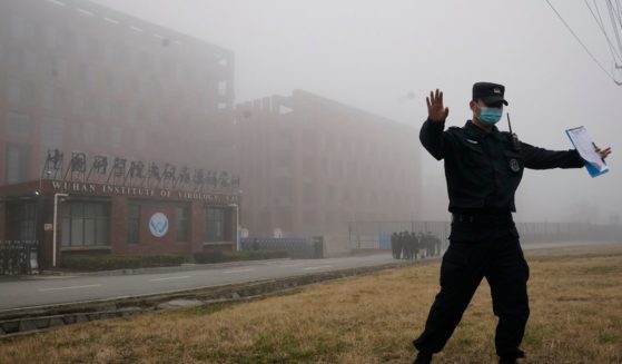 A security official moves journalists away from the Wuhan Institute of Virology in Wuhan in China's Hubei province on Feb. 3, 2021.