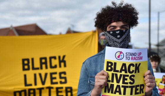 A person holds up a Black Lives Matter placard as they attend a "Take The Knee" event outside Southend Victoria Station on May 25, 2021, in Southend-on-Sea, England.