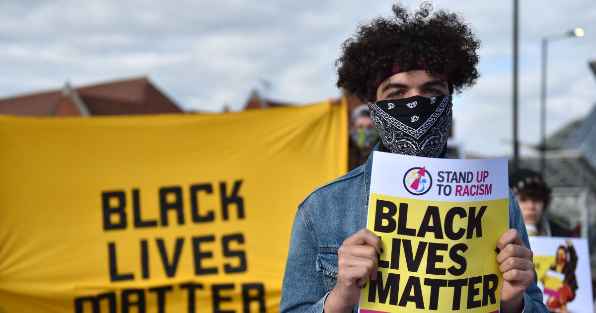 A person holds up a Black Lives Matter placard as they attend a "Take The Knee" event outside Southend Victoria Station on May 25, 2021, in Southend-on-Sea, England.