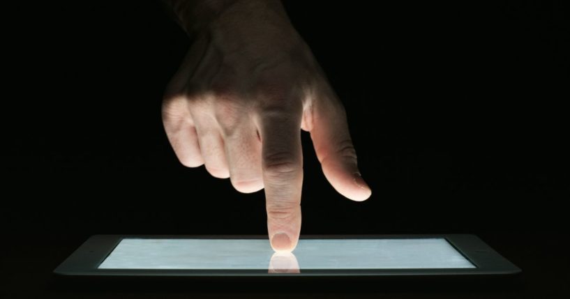 A man uses a tablet in the above stock image.