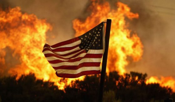 An American flag is seen in the foreground as a wildfire burns near Acton, California, on July 20, 2004.