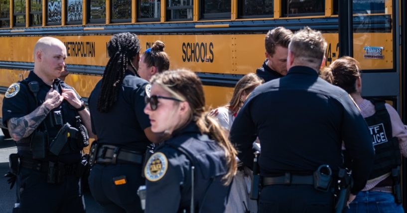 Nashville police officers are on guard as buses with children from The Covenant School arrive at a family reunification center on Monday after a shooting that left three children and three adults dead.