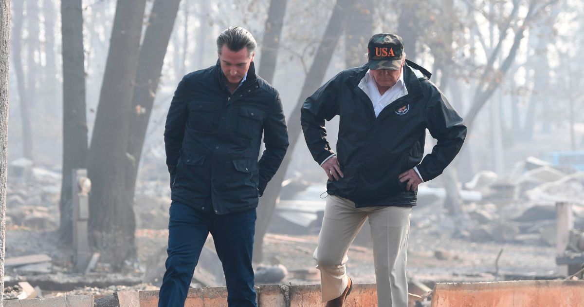 Donald Trump walks with then-Lieutenant Governor of California, Gavin Newsom, as they view damage from wildfires in Paradise, California on November 17, 2018.
