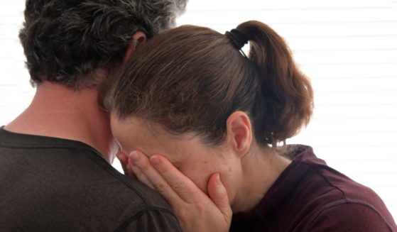 A woman cries while being embraced by a man in this stock image.