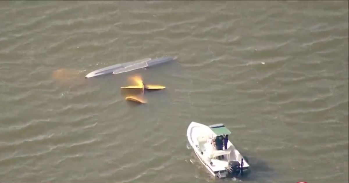 Search and rescue personnel approaching the partially submerged wreckage of a crashed plane