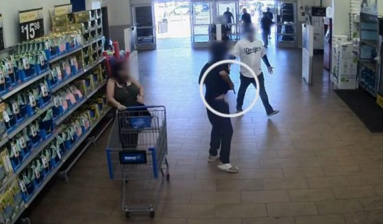 This YouTube screen shot of Walmart surveillance footage shows a police officer and loss prevention employee confronting a suspected shoplifter with a gun.