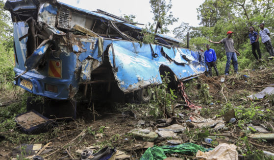 People observe the wreckage at the scene of a bus crash involving dozens of mourners who were returning from a funeral, near Mwatate, Kenya, on Saturday.