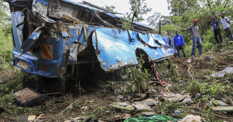 People observe the wreckage at the scene of a bus crash involving dozens of mourners who were returning from a funeral, near Mwatate, Kenya, on Saturday.