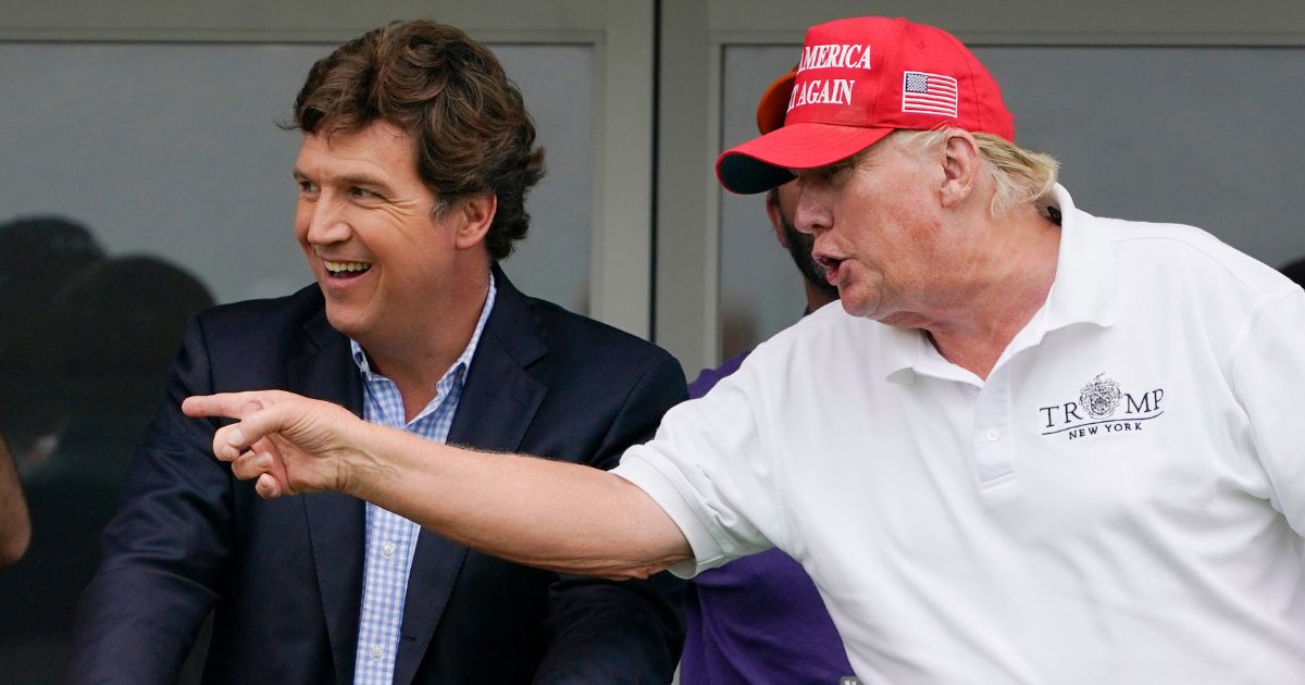 Tucker Carlson, left, and former President Donald Trump talk while watching golfers on the 16th tee during the final round of the LIV Golf Invitational at Trump National in Bedminster, New Jersey, on July 31.