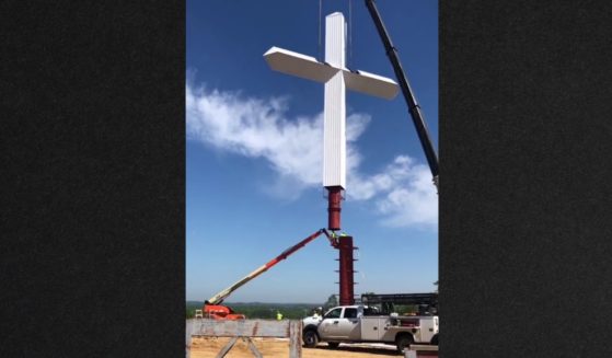 Hundreds stopped to watch a crew raise the cross Thursday in Priceville, Alabama.