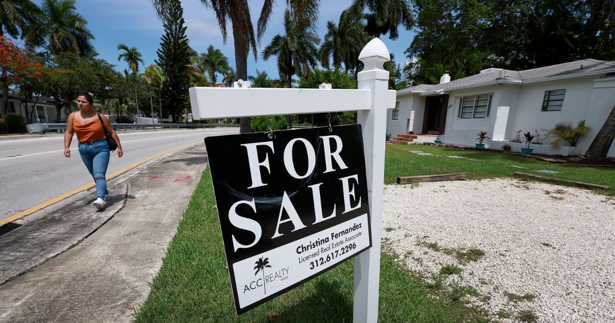 A "For Sale" sign hangs in front of a home in Miami on June 21, 2022.