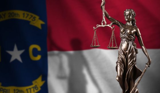 A statue of Lady Justice is seen in front of the North Carolina state flag in the above stock image.