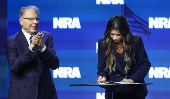 With NRA CEO Wayne LaPierre by her side, South Dakota Gov. Kristi Noem signs an executive order to protect gun rights in her state at the 2023 NRA-ILA Leadership Forum on Friday in Indianapolis.