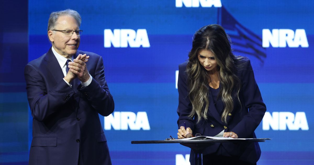 With NRA CEO Wayne LaPierre by her side, South Dakota Gov. Kristi Noem signs an executive order to protect gun rights in her state at the 2023 NRA-ILA Leadership Forum on Friday in Indianapolis.