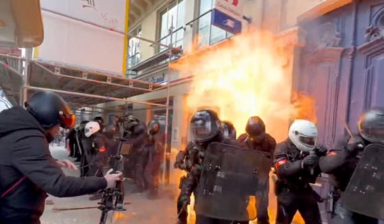 A police officer's uniform is partially set on fire amid protests and riots in Paris on Thursday.