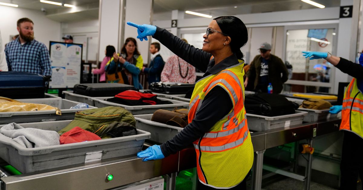 A worker points as people wait for their belongings at the Transportation Security Administration security area at Atlanta's airport on Jan. 25.