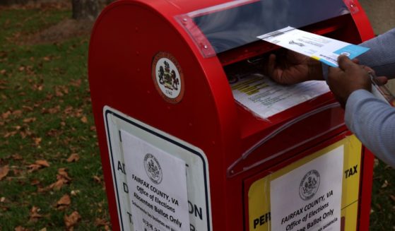 A voter puts an absentee ballot into a collection bin outside the Fairfax County Government Center in Fairfax, Virginia, on Oct. 19, 2020.
