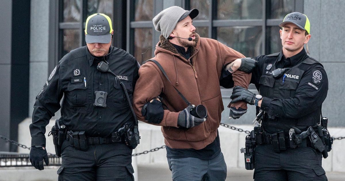 Pastor Derick Reimer, middle, is seen with police in Canada.
