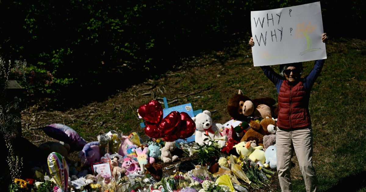 Mary Habibian holds a sign that read "Why? Why?" at a makeshift memorial for victims of a shooting at the Covenant School campus, in Nashville, Tennessee, March 29, 2023. (Brendan Smialowski - AFP / Getty Images)