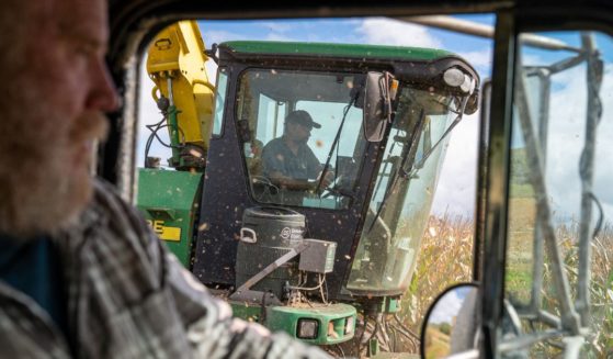 Farmer and landowner Robert Mack, left, drives a truck next to a harvester combine tractor that cuts and loads corn silage September 29, 2022 in Charlotte, Vermont.