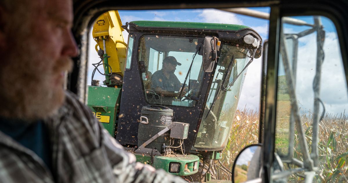 Farmer and landowner Robert Mack, left, drives a truck next to a harvester combine tractor that cuts and loads corn silage September 29, 2022 in Charlotte, Vermont.