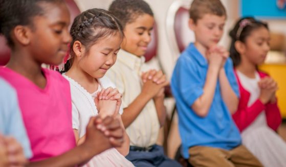 The above stock image shows children praying.